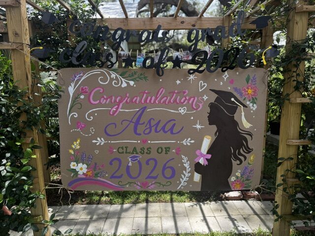 Congratulations Asia Class of 2026 graduation banner hung outdoors on a garden trellis